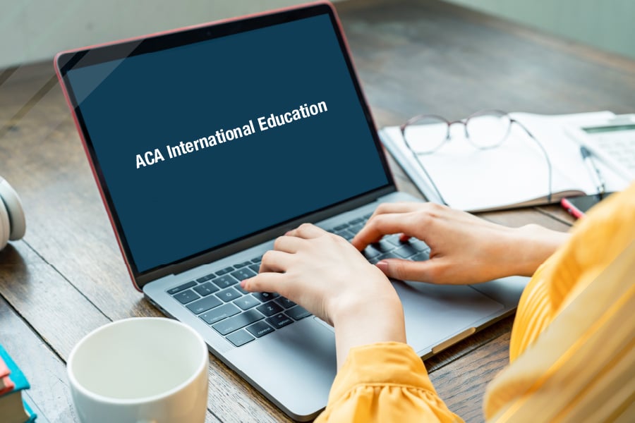 woman typing on a laptop that says "ACA International Education"