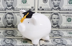 piggy bank with graduation cap on pile of money